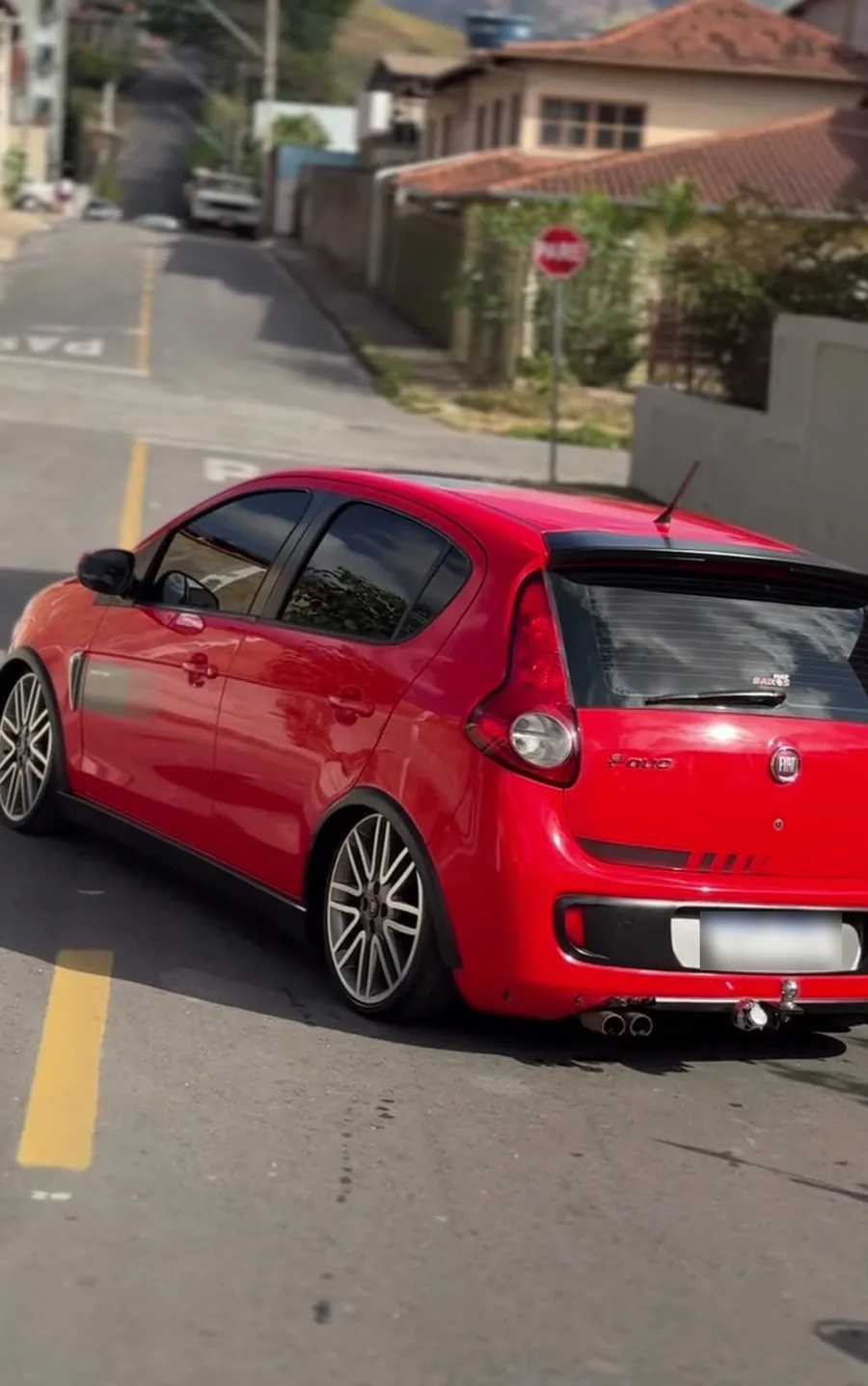 Fiat Palio vermelho rebaixado, com rodas de liga, estacionado em uma rua