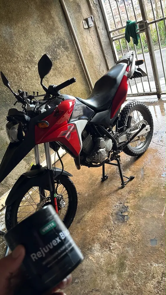 Moto vermelha na garagem com um pote de produto de limpeza em primeiro plano